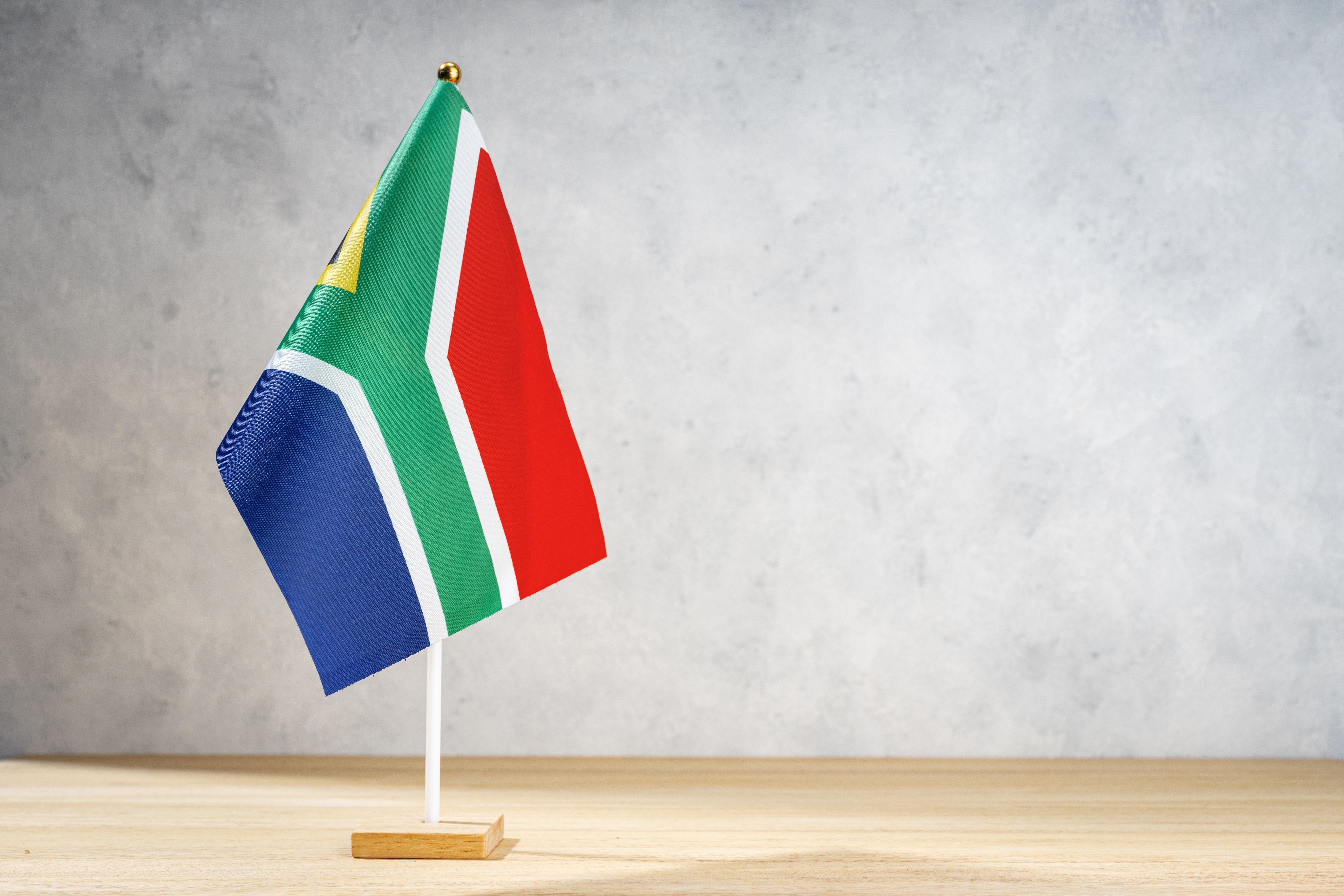 south-africa-table-flag-on-white-textured-wall-2025-02-21-00-24-32-utc